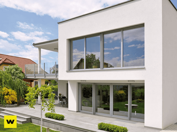 Modernes Einfamilienhaus mit großer Glasfassade, Terrasse und gepflegtem Garten.