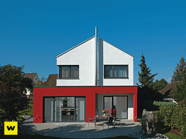 Modernes Einfamilienhaus mit roter Fassade und großen Fenstern im grünen Garten.