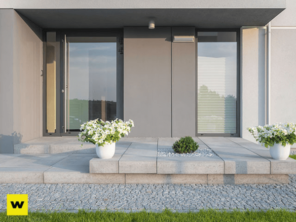 Moderner Hauseingang mit großen Glasflächen, Pflanzkübeln und minimalistischer Gartengestaltung.