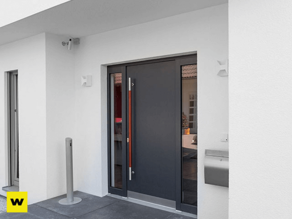 Moderne Haustür aus Aluminium mit Seitenteil in weißer Hausfassade und Edelstahlgriff.